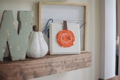 an orange piece of string is hanging on the mantle next to a small white pumpkin