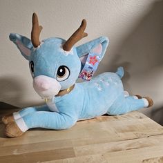 a blue stuffed animal laying on top of a wooden table