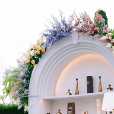 a white shelf with bottles and flowers on it