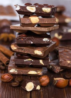 chocolate bars stacked on top of each other with nuts and cinnamons in the background