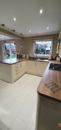 a kitchen with white tile flooring and wooden counter tops