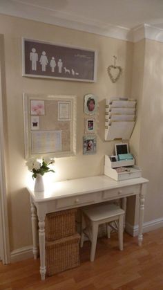 a white desk with flowers and pictures on the wall next to an entryway door