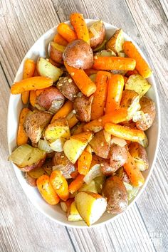 a bowl filled with potatoes and carrots on top of a wooden table