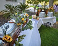 the table is set up with sunflowers and other flowers in vases on it