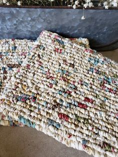 an old rug is laying on the floor next to a planter with flowers in it