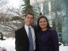 a man and woman standing next to each other in front of a building with snow on the ground