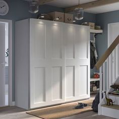 an open closet with white doors and drawers in a living room next to a staircase