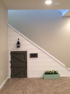 an empty room with a door and planter under the stair case in front of it