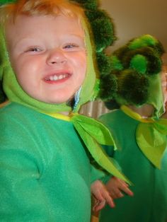 a young child wearing a green costume and smiling at the camera