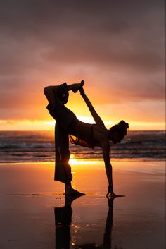 a woman doing yoga on the beach at sunset