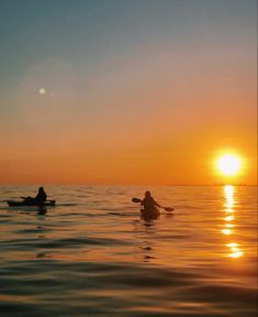 two people are paddling on their surfboards in the ocean at sunset or dawn