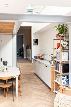 an open kitchen and dining room with white walls, wood flooring and wooden furniture