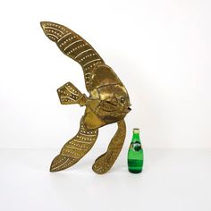 a gold fish statue next to a green bottle