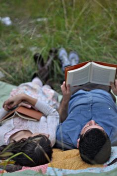 a man laying on the ground reading a book