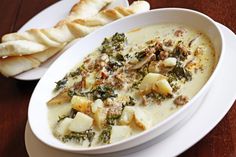 a white bowl filled with soup next to some bread