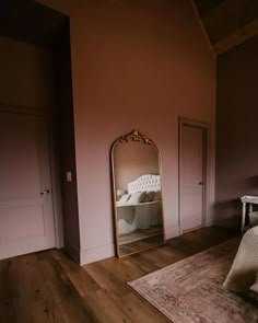 a bedroom with a bed, mirror and chair on the floor in front of it