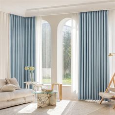 a living room filled with furniture and windows covered in blue drapes on top of them