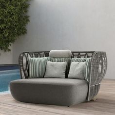 a couch sitting next to a swimming pool on top of a hard wood floor covered in pillows