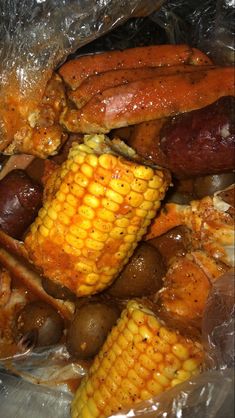 corn on the cob and sausages wrapped in plastic wrapper, ready to be cooked