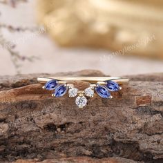 a gold ring with two blue and white stones on it, sitting on top of a piece of wood