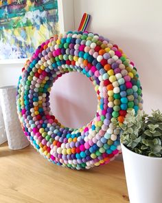 a wreath made out of colored pebbles next to a potted plant