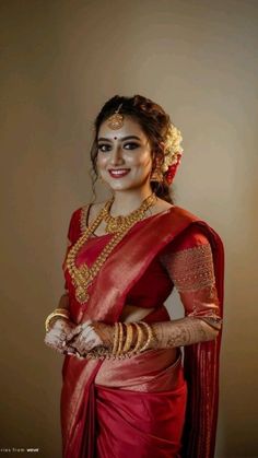 a woman wearing a red sari and gold jewelry