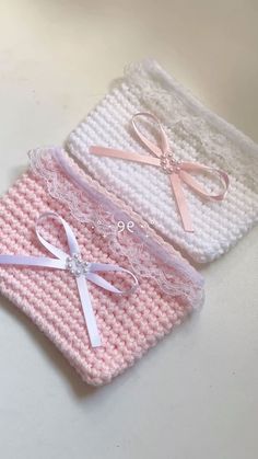 two pink and white crocheted baby blankets with bows on them, one has a diamond brooch