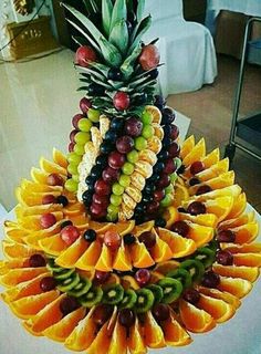 a pineapple and grapes are arranged in the shape of a fruit pyramid on a table