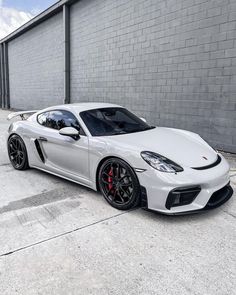 a white sports car parked in front of a brick building with black rims and red brake pads