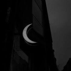 a black and white photo of a clock on the side of a building at night