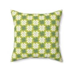 a green and white pillow with four leaf clovers on the front, in an ornate pattern