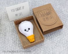 a small stuffed animal in a box with a note on the front and back side