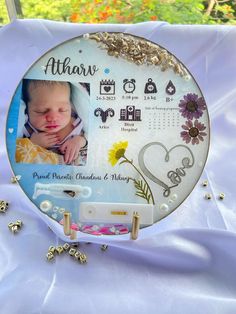 a baby's photo is displayed on a plate with beads and other items around it