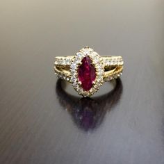 a close up of a ring with a red stone on the middle and white diamonds around it