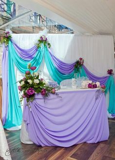 the table is covered with purple and blue draping for an elegant wedding reception