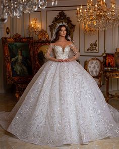 a woman in a white wedding dress standing next to a chandelier