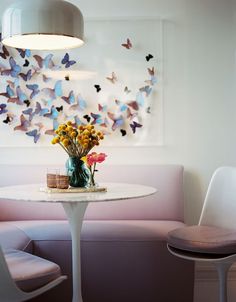 a white table with flowers and butterflies on the wall behind it in a living room