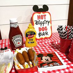 a table topped with hot dogs and ketchup on top of a checkered table cloth