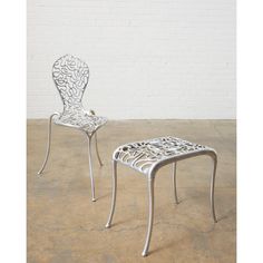 two white metal chairs sitting next to each other