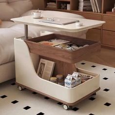 a coffee table that is on wheels with magazines and drinks in the bottom drawer, next to a couch