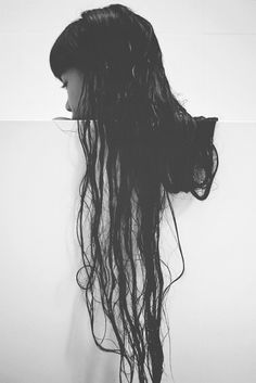 the back of a woman's head is shown with long hair flowing down it