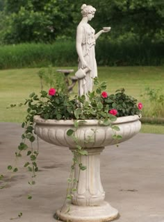 there is a statue in the middle of a planter with roses growing out of it