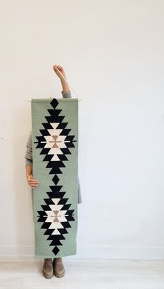 a woman is holding up a green and white blanket that has an arrow on it