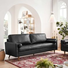 a black leather couch sitting on top of a red rug