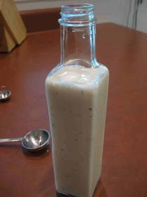 a glass bottle filled with milk sitting on top of a table next to a spoon