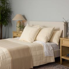 a bed with white sheets and pillows in a bedroom