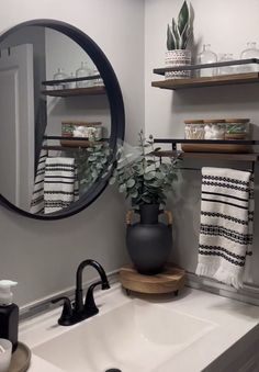 a bathroom sink sitting under a round mirror