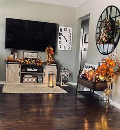 the living room is decorated for fall with decorations on the tv stand and wreaths