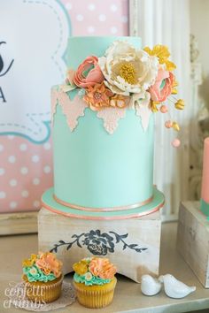 two cupcakes sitting on top of a table next to a blue and pink cake