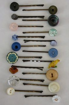 several different types of sewing needles are arranged on a white surface with buttons and thread spools